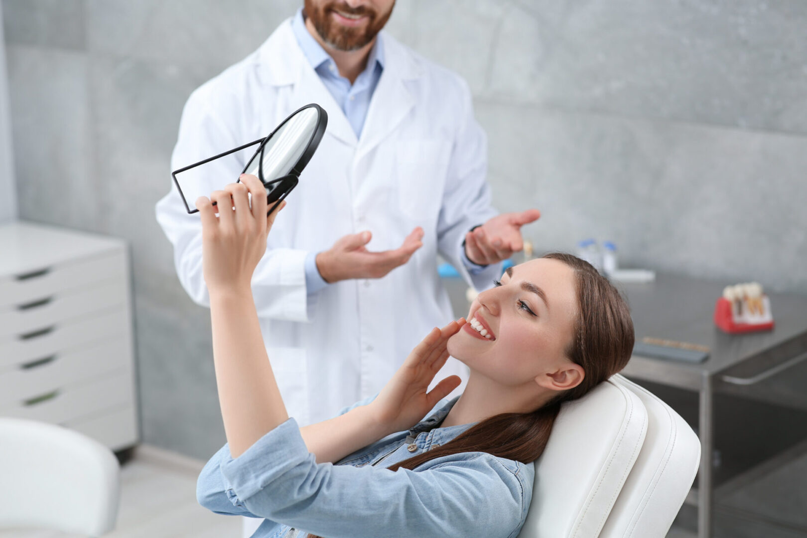 Dentist explaining dental care to a female patient using a dental model.