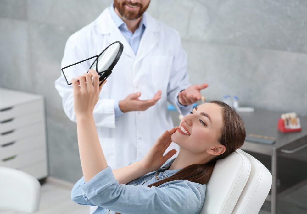 Dentist explaining dental care to a female patient using a dental model.